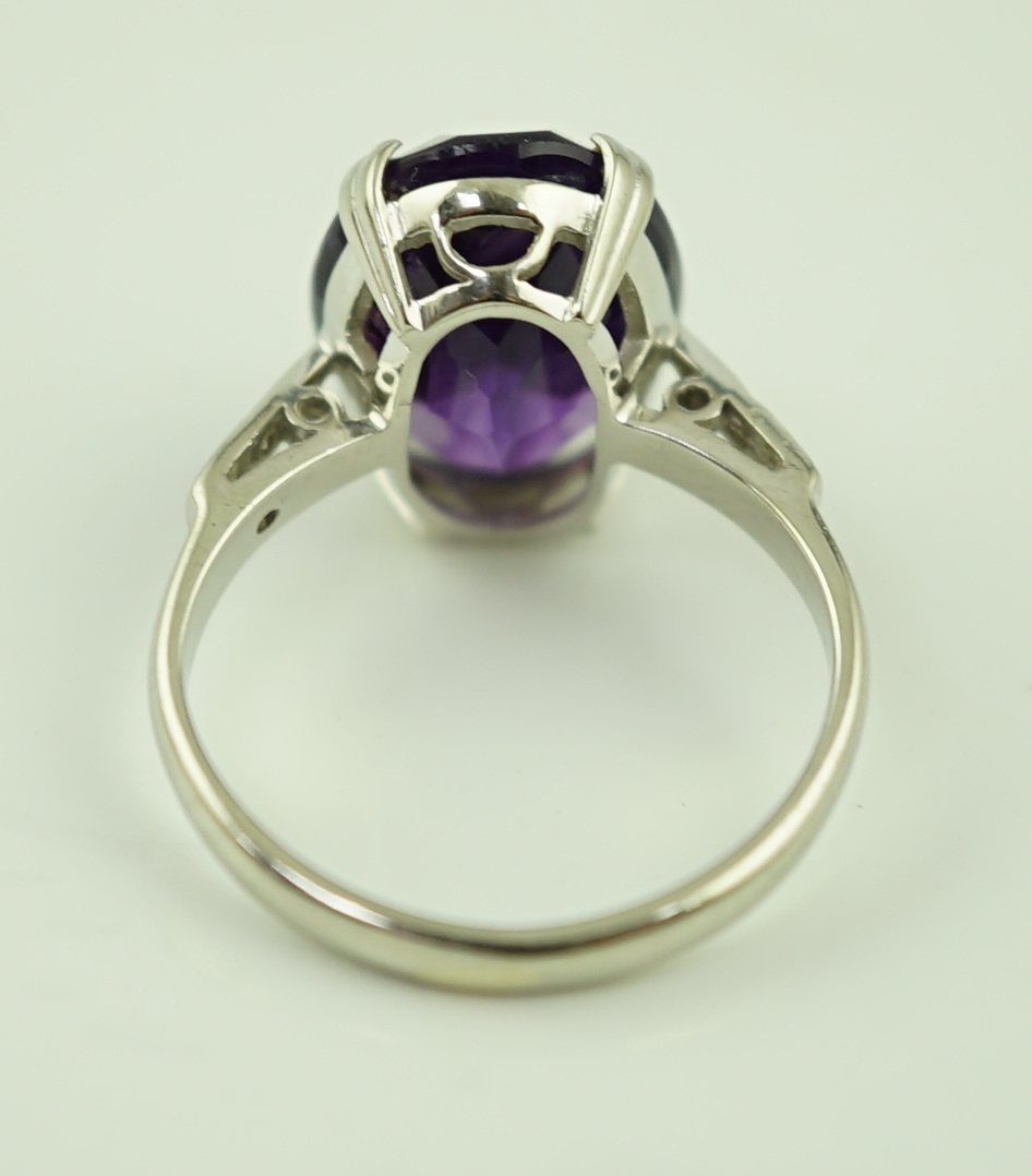 An 18ct white gold and oval cut amethyst set ring, with two stone diamond chip set shoulders